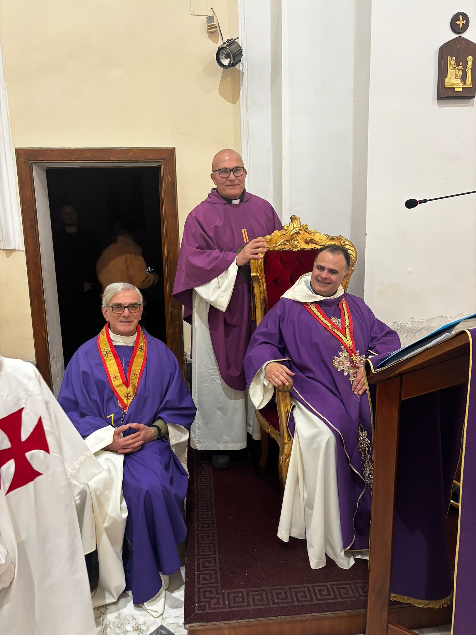 Cappellani e dignitari templari in veste viola seduti sul trono